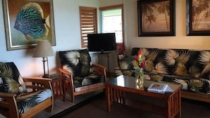 Een woonkamer met een bank, stoelen, een salontafel en een televisie.