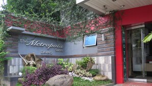 Een hotelentree met een bord waarop 'The Metropolis Davao Suites' staat.