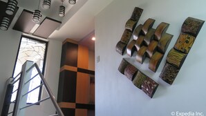 Een modern interieur met een trap, decoratieve muurkunst en hangende pendelverlichting.