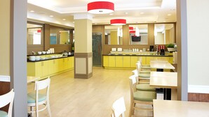 A modern dining area with yellow cabinets, white chairs, and a central island with a sink. - Eco Hotel (Pohang)