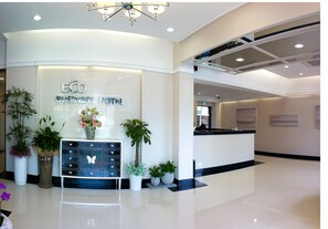 A reception area with a modern design, featuring a reception desk, potted plants, and a sign that reads "ECO BUSINESS HOTEL". - Eco Hotel (Pohang)