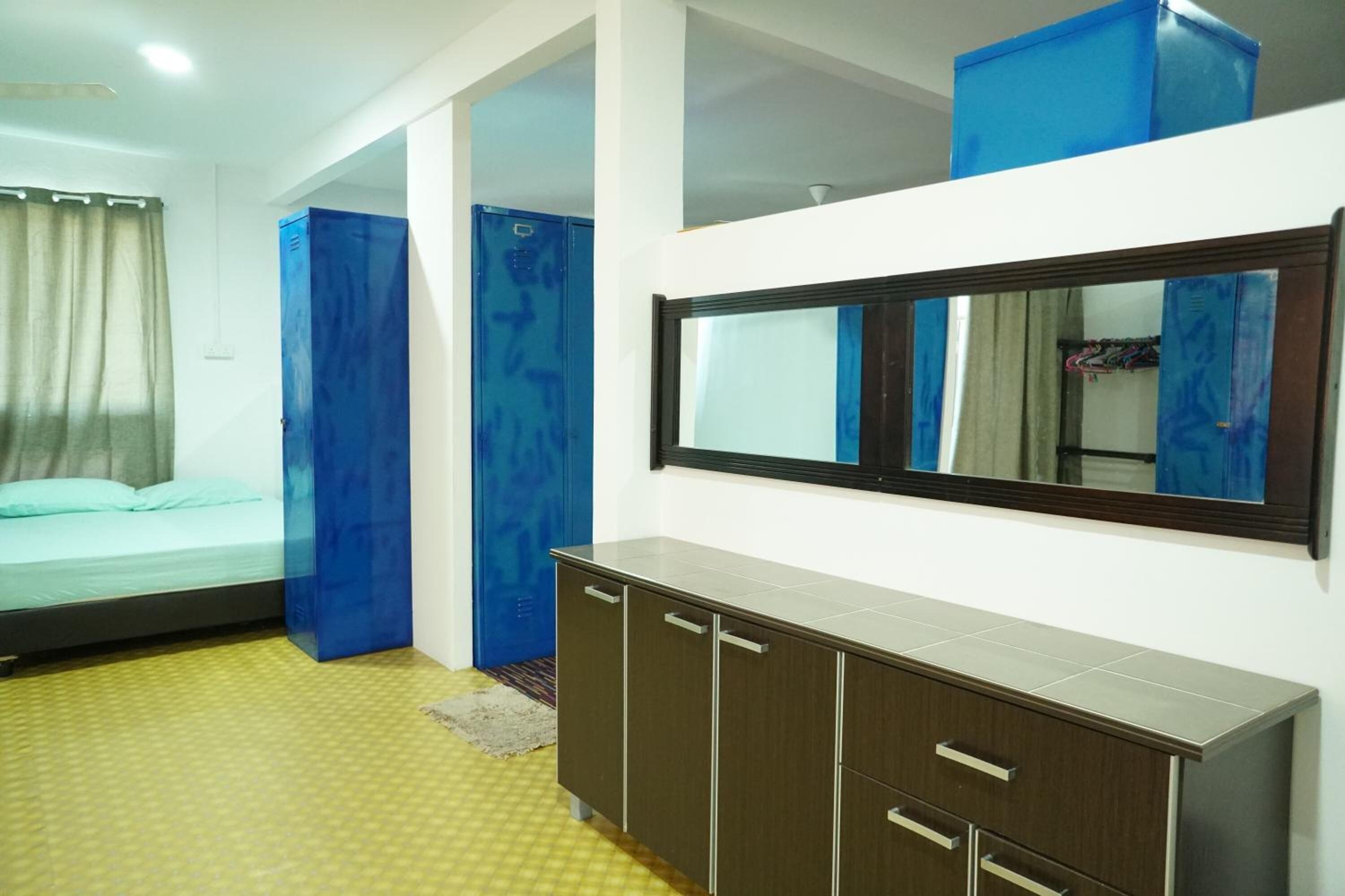 Une chambre à coucher avec un lit, une armoire et un miroir au mur.