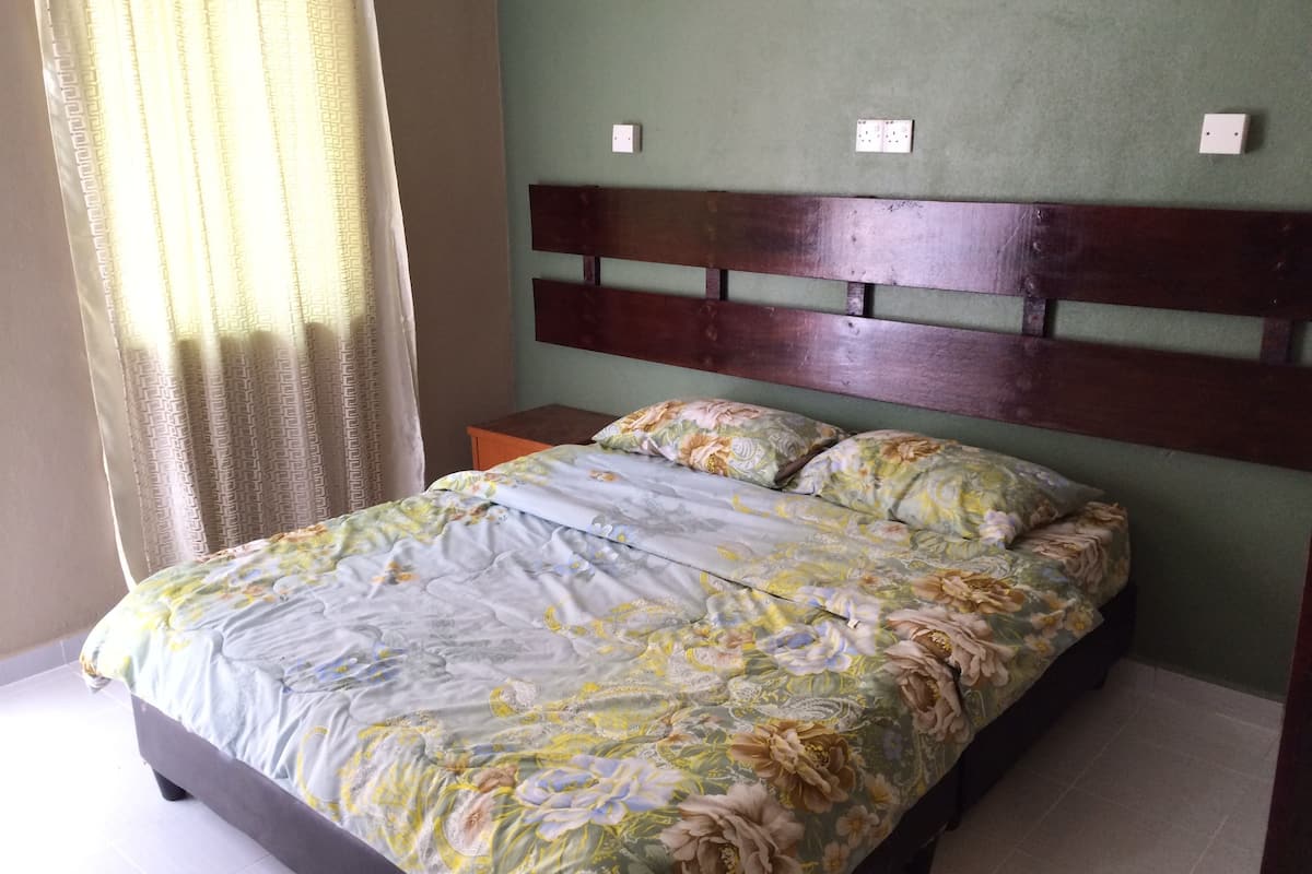 A bed with floral bedding, a wooden headboard, and a nightstand with a lamp.