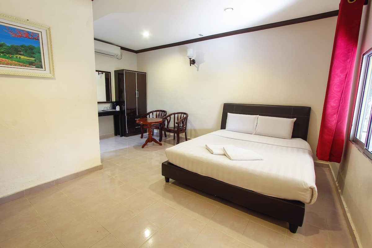 A bedroom with a bed, a desk, a chair, a wardrobe, and a painting on the wall.