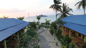 A pathway leading to a beachside building with a blue roof, surrounded by palm trees and a view of the sea. - Tanjung Puteri Motel (Langkawi)
