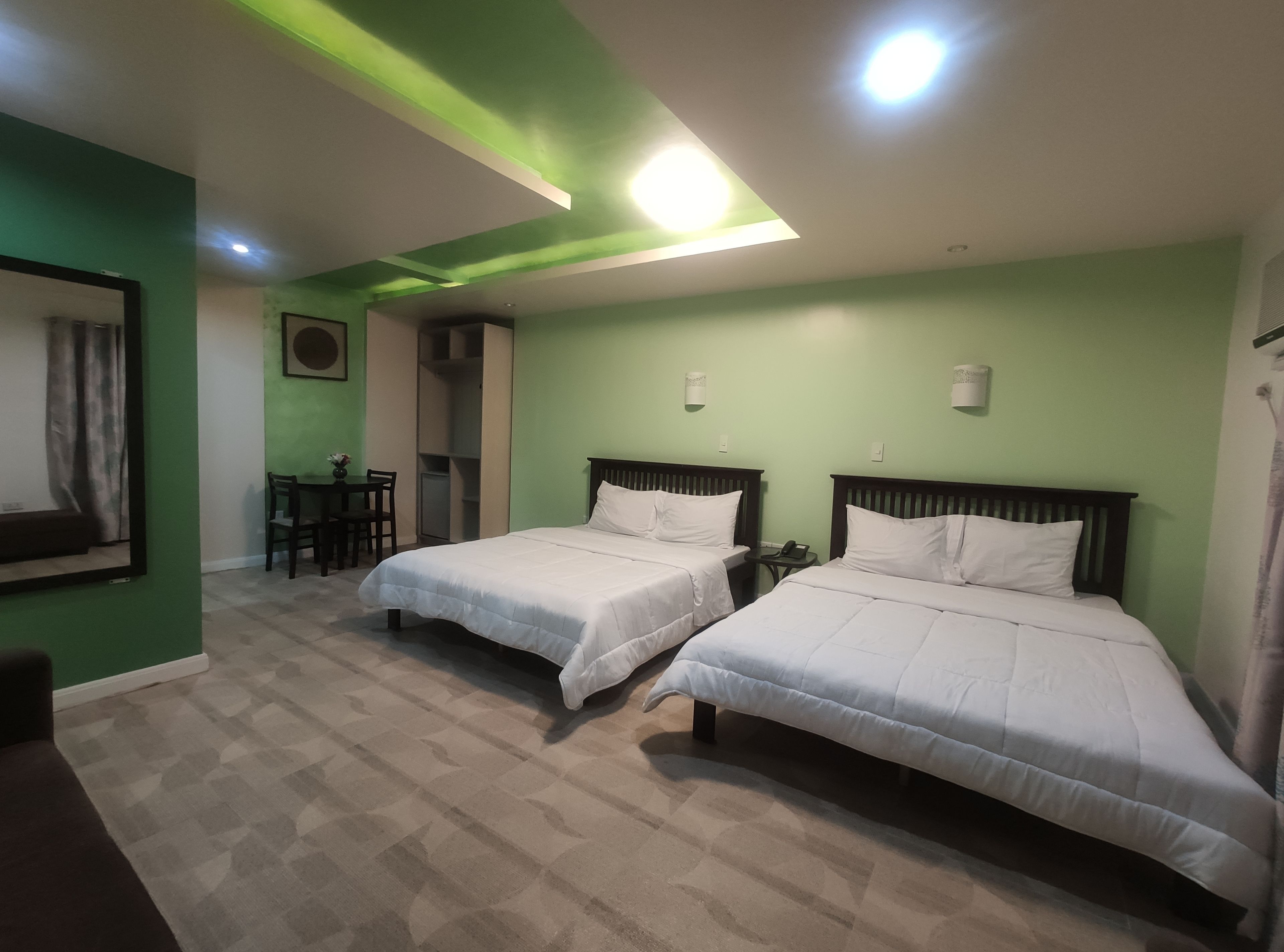 A hotel room with two single beds, a desk with a chair, and a small table.