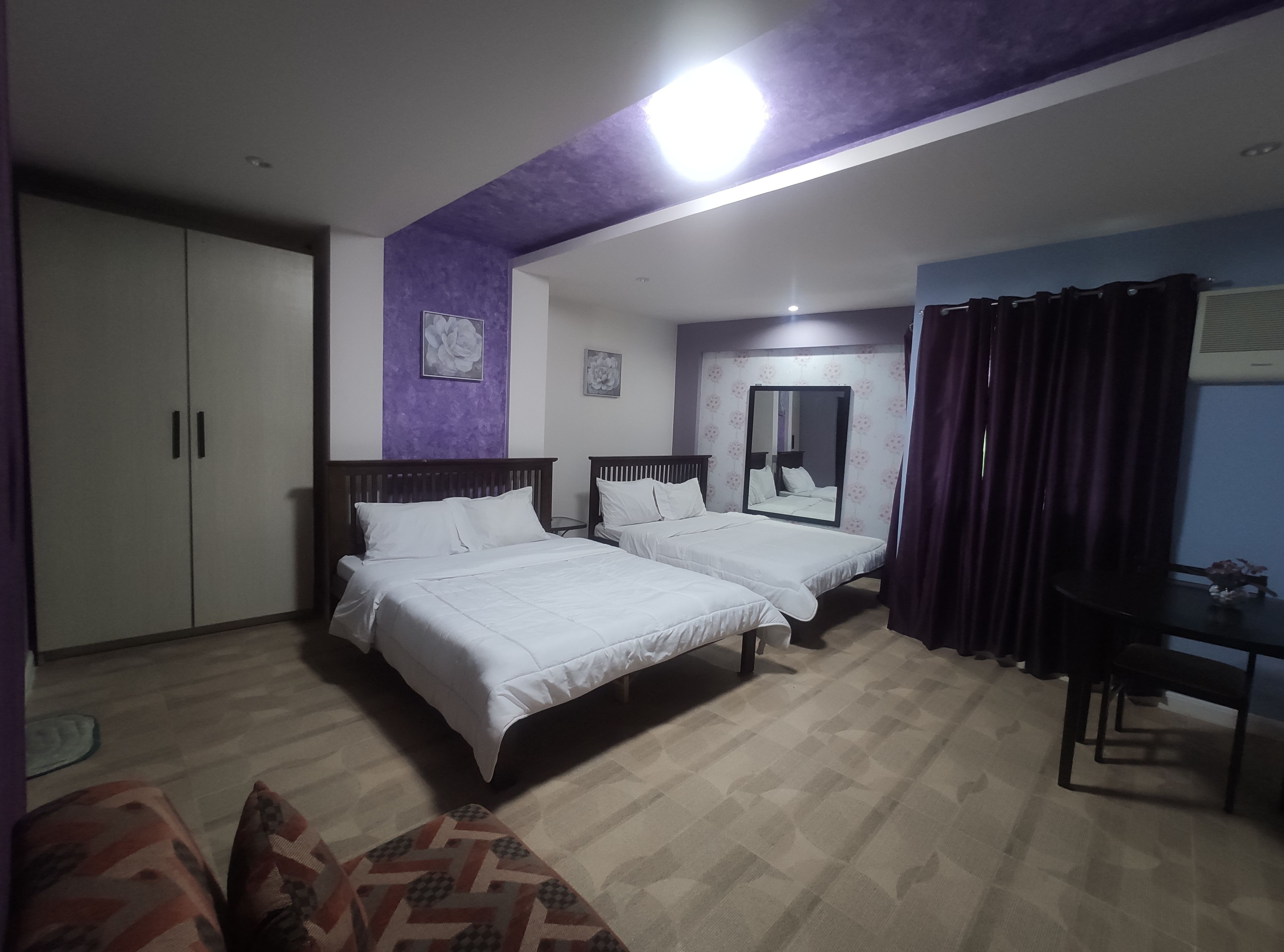 Habitación de hotel con dos camas, un escritorio, una silla y un armario.