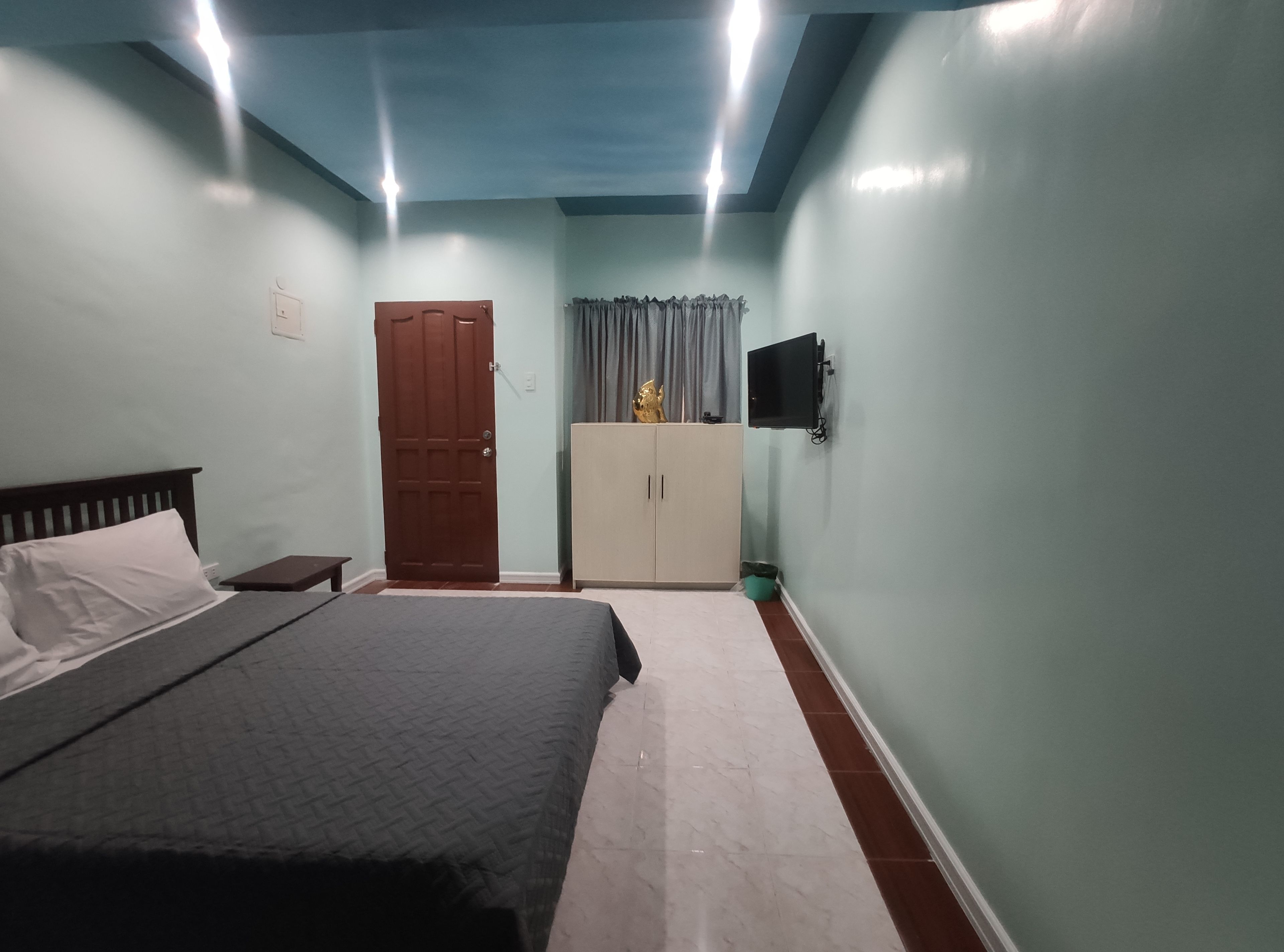 A bedroom with a bed, a wardrobe, a television, and a ceiling light.