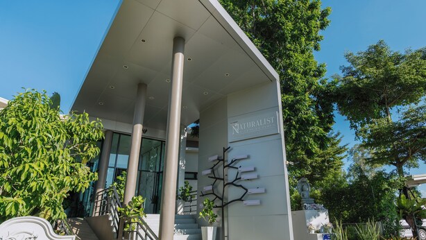A modern building with a covered entrance, a staircase, and a wall-mounted sculpture.