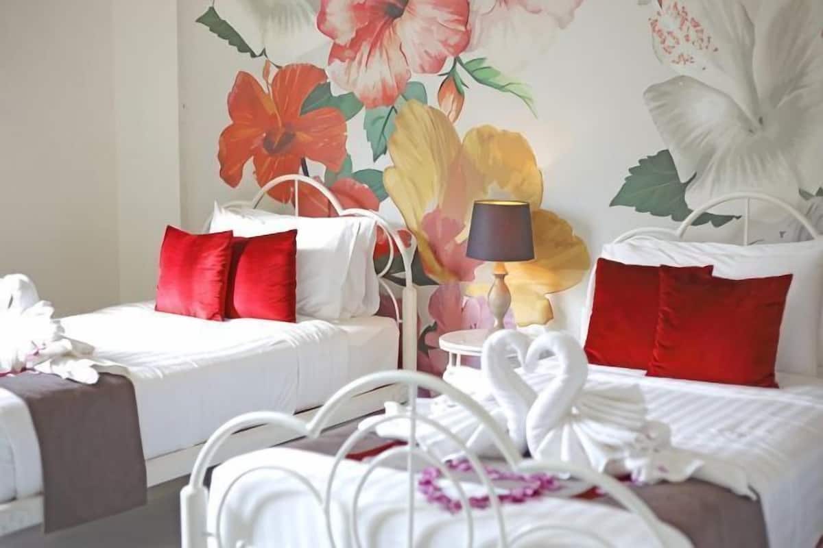 Habitación de hotel con dos camas, un mural floral y una lámpara.