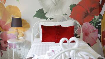 A neatly made bed with a white headboard, red pillows, and a white towel.