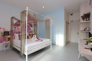 A four-poster bed with a canopy, a bedside table with a lamp, and a wall with floral wallpaper. - Play La Ploen Boutique Resort (Khu Mueang)