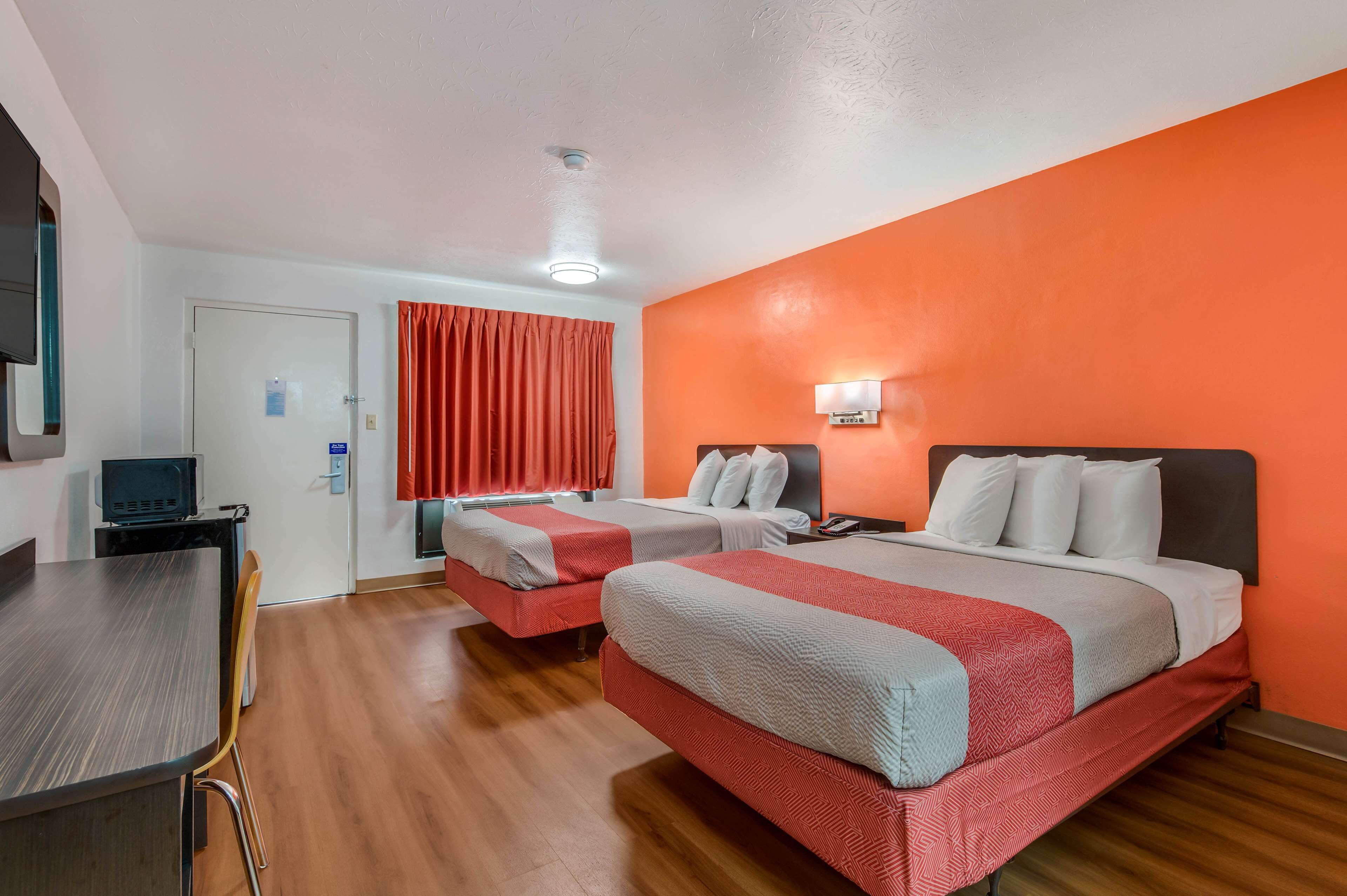 A hotel room with two beds, a desk, and a television.