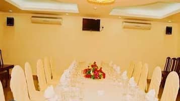 A long dining table set for a formal event, with white tablecloths and chairs, and a floral centerpiece.