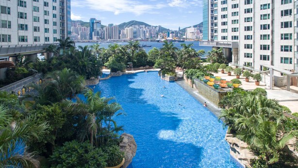 A large indoor swimming pool surrounded by lush greenery and modern buildings. - Kowloon Harbourfront Hotel (Kowloon)