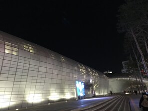 A modern building with a grid-like facade and a large illuminated screen.