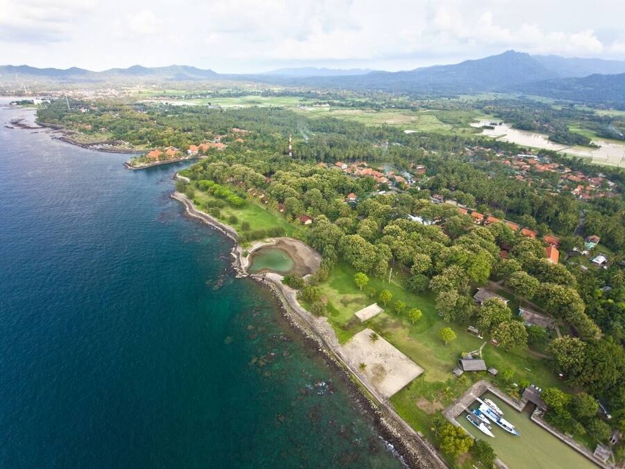 An aerial view of a coastal area with a marina, residential buildings, and a large park.