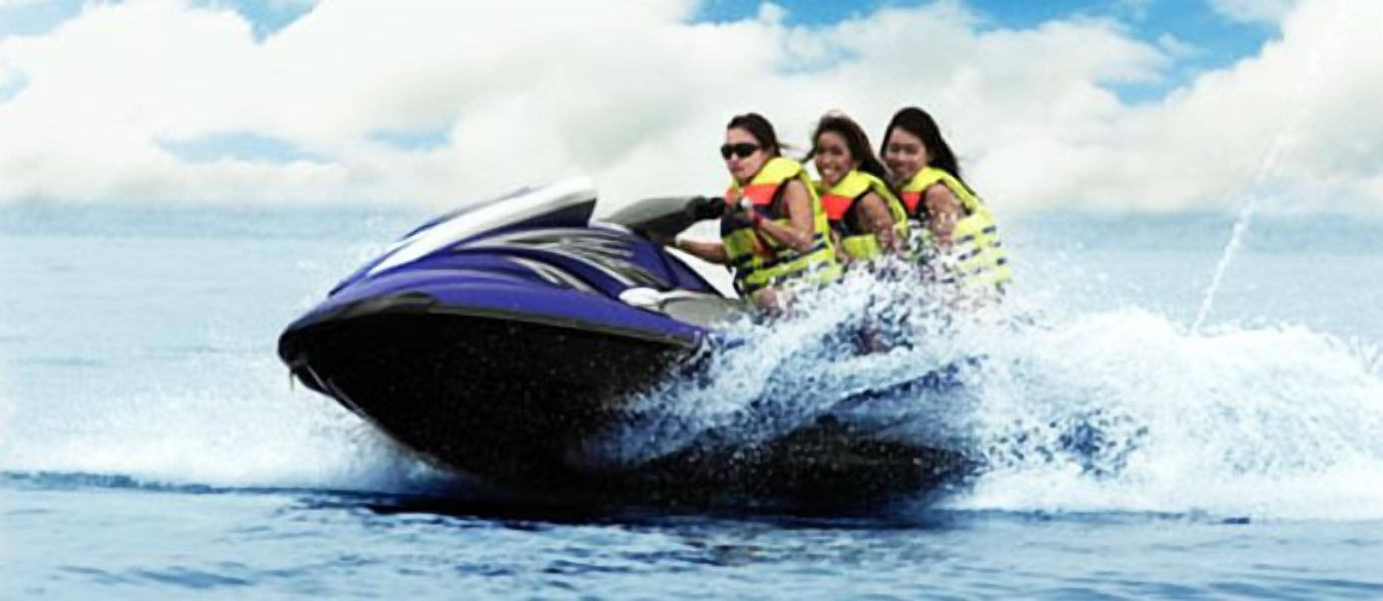 A jet ski with passengers wearing life jackets.