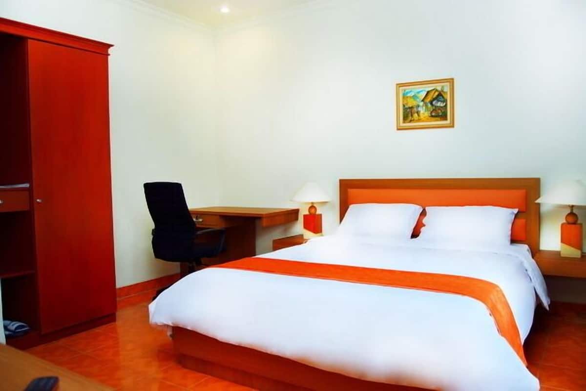 Una habitación de hotel con una cama, un escritorio, una silla y un armario.
