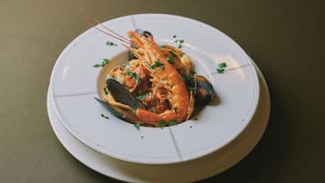 En tallerken med fisk og skaldyr, herunder rejer og muslinger, pyntet med krydderurter.