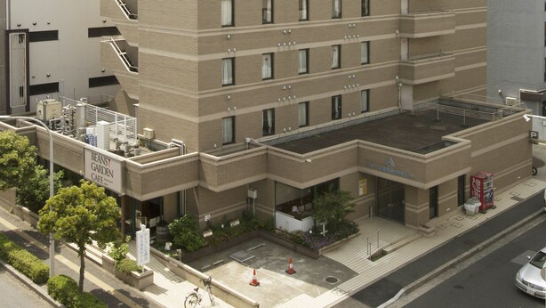 A multi-story hotel with a flat roof, a sign for a cafe, and a parking lot.