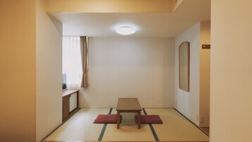 Una habitación con suelo de tatami, una mesa de madera baja y un espejo en la pared.