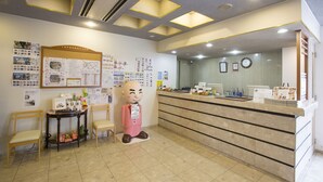 A reception area with a large information board, a reception desk, and a statue of a man.