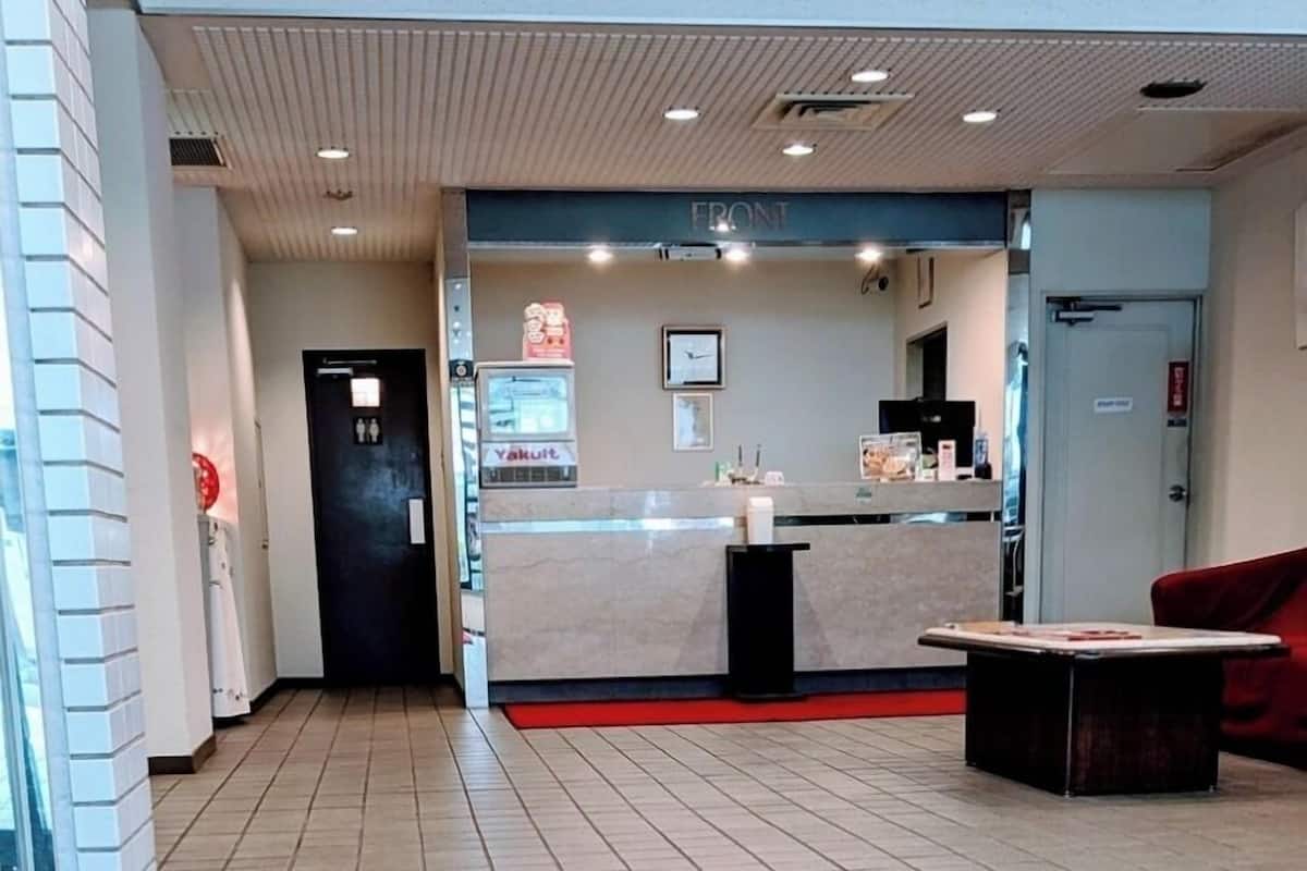 Un hall d’hôtel avec un comptoir d’accueil, une horloge et un tapis rouge.