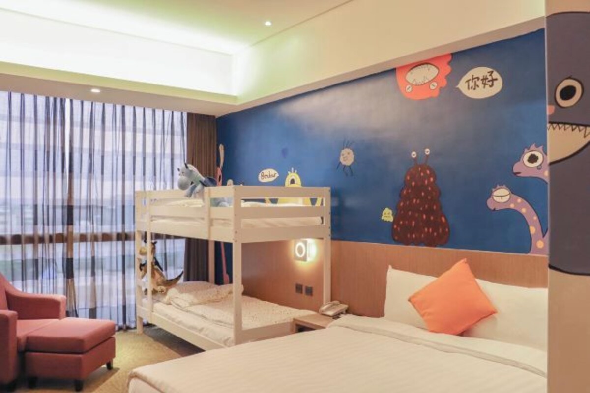 Una habitación de hotel con literas, un escritorio, una silla y una pared con personajes de dibujos animados.