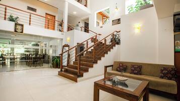 A spacious lobby with a staircase, a seating area, and a glass coffee table.