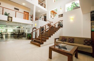 Un vestíbulo amplio con una escalera, una zona de estar y una mesa de centro de vidrio.