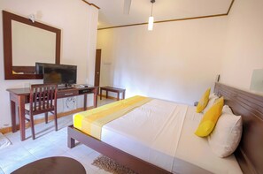 A bedroom with a bed, a desk, a chair, a television, and a mirror. - Lavendish Okrin Hotel (Kataragama)