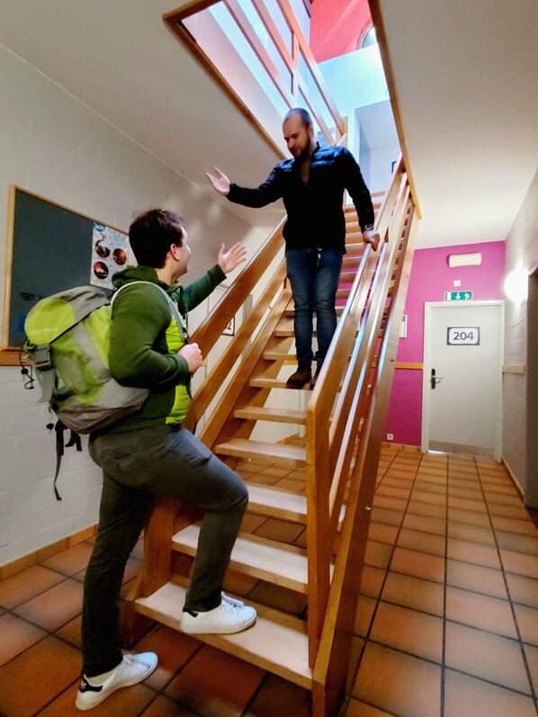 Una escalera con barandillas de madera y una persona subiendo.