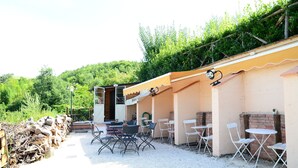 An outdoor patio with tables and chairs, a covered seating area, and a gravel path. - Selvicolle Country House (Castelraimondo)