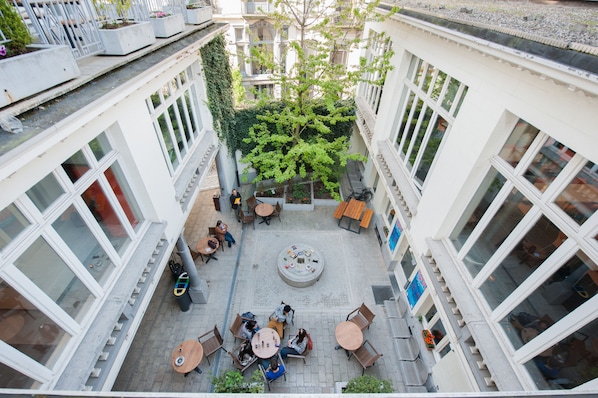 A courtyard with outdoor seating, a central fire pit, and surrounding greenery. - Jacques Brel Youth Hostel (Brussels)