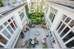 Un patio con mobiliario exterior, una chimenea en el centro y vegetación circundante.