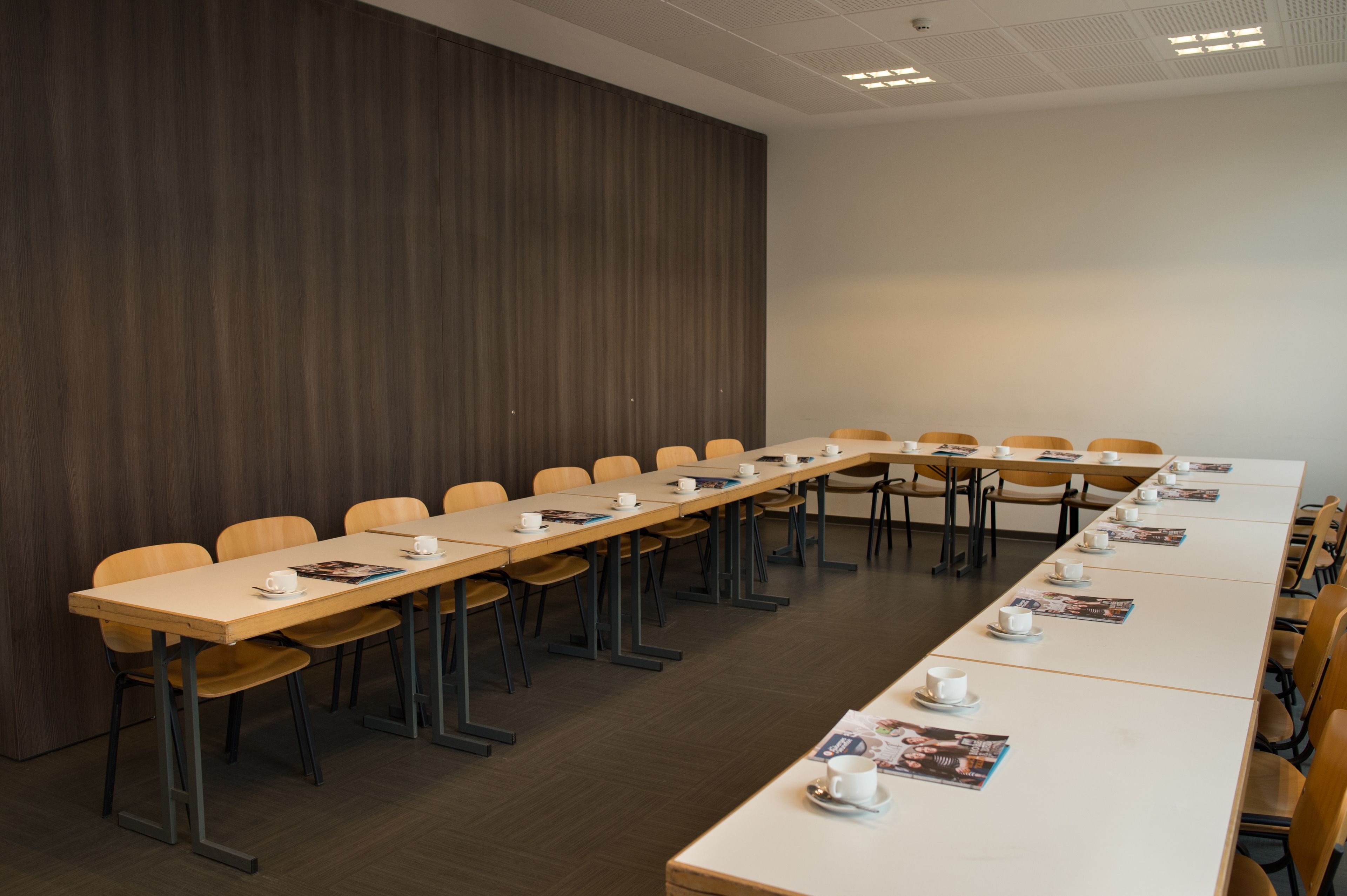 A conference room with a long table, chairs, and a wooden panel wall.