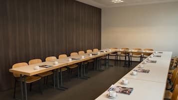 Un salón de conferencias con una mesa larga, sillas y un panel de pared de madera.