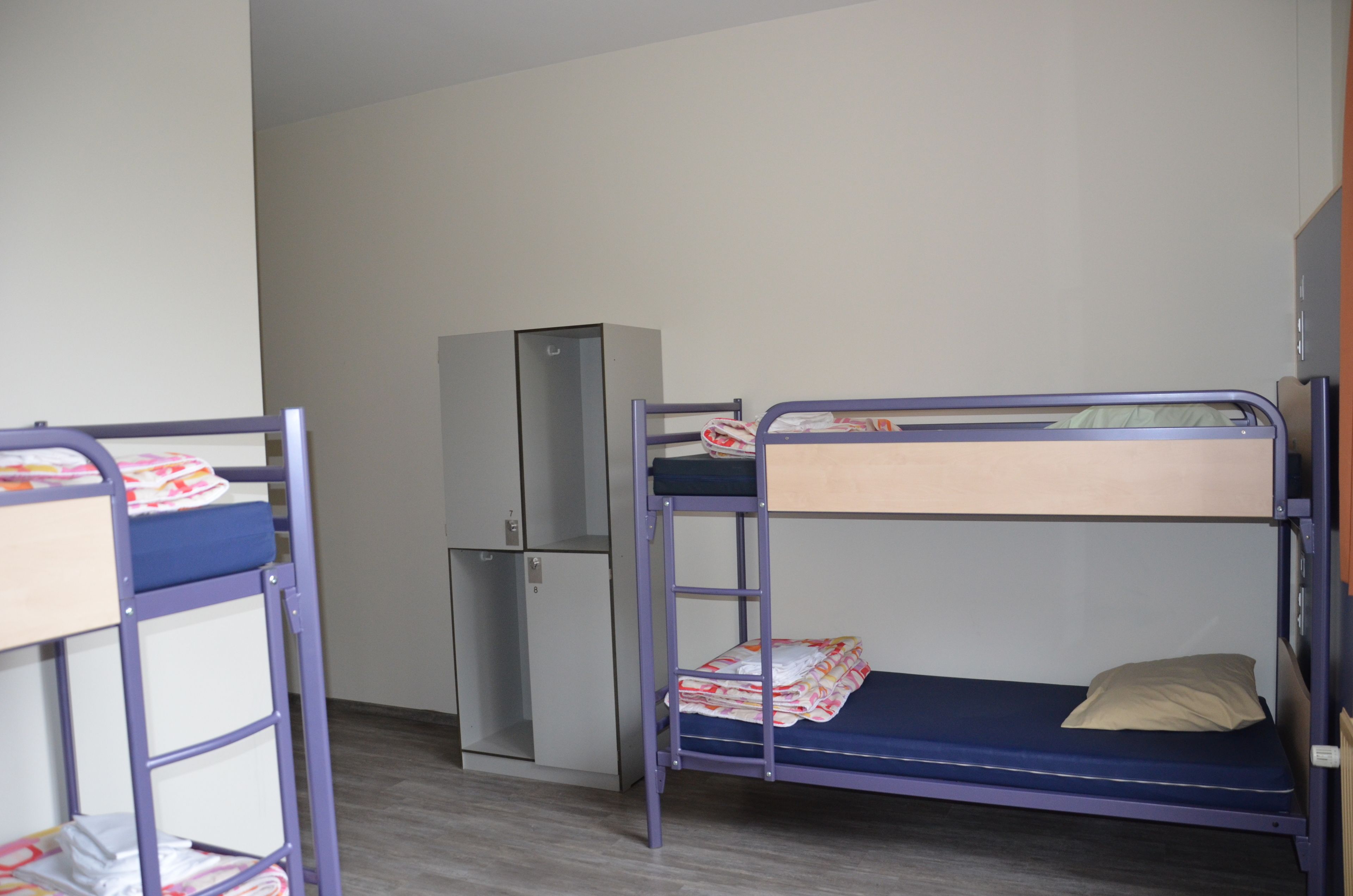 Ein Zimmer mit Etagenbetten, einem Kühlschrank und einem Schrank.
