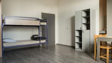 Een stapelbed met een bureau en een boekenkast in een kamer met houten vloeren.