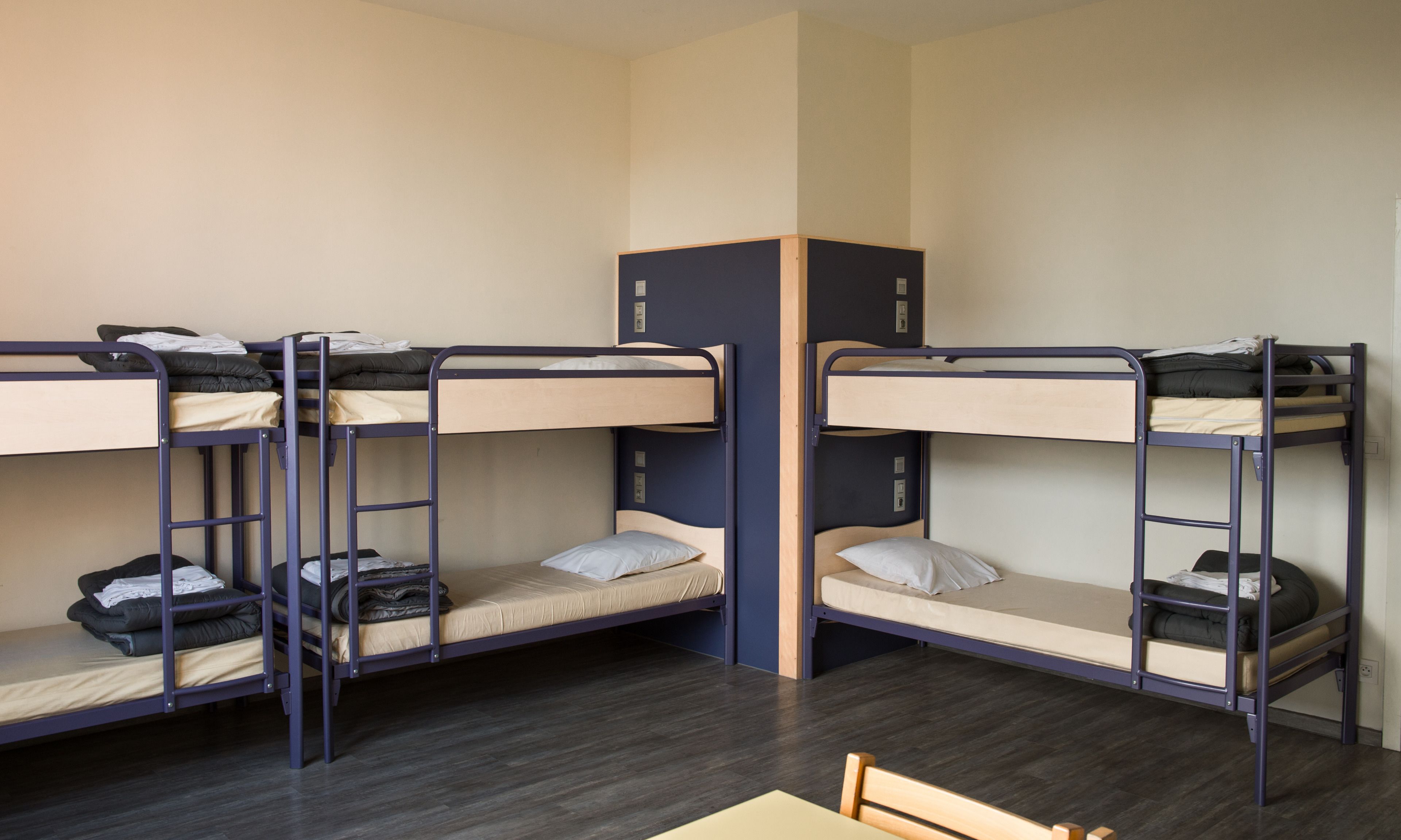 A dormitory room with bunk beds, a desk, and a chair.