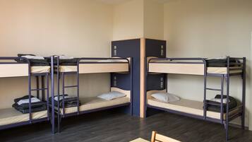 A dormitory room with bunk beds, a desk, and a chair.