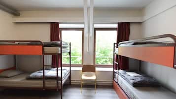 Un dormitorio con literas, una silla y una ventana con cortinas.