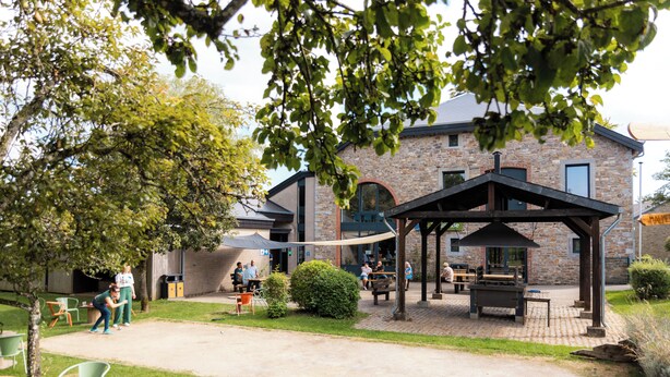 Un espace extérieur aménagé avec des sièges, un bâtiment en pierre et un kiosque.