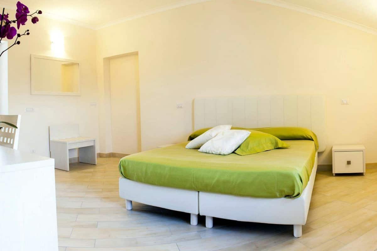 A bedroom with a bed, bedside tables, a nightstand, and a mirror.