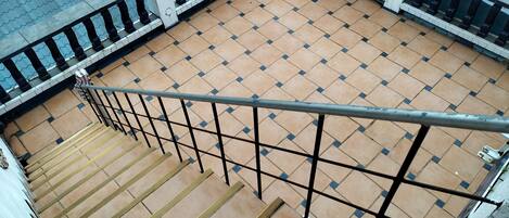 A tiled outdoor area with a metal railing and a staircase leading down.