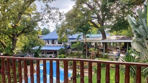 A pool with a wooden railing, surrounded by lush greenery and a house with a blue roof. - Princess of Coron (Coron)