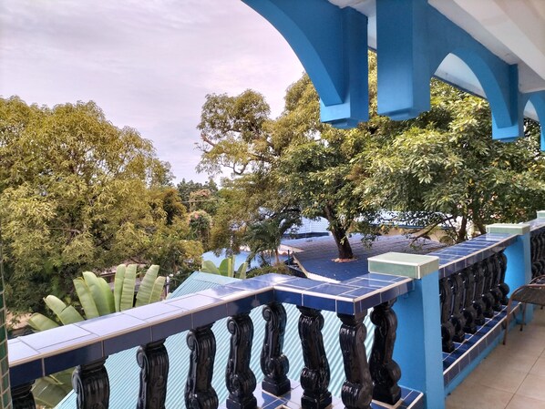 A balcony with blue railings and a view of trees and a building in the background. - Princess of Coron (Coron)