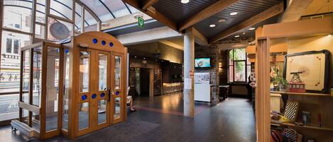 A spacious lobby with a wooden reception desk, a glass door entrance, and a seating area with a television.