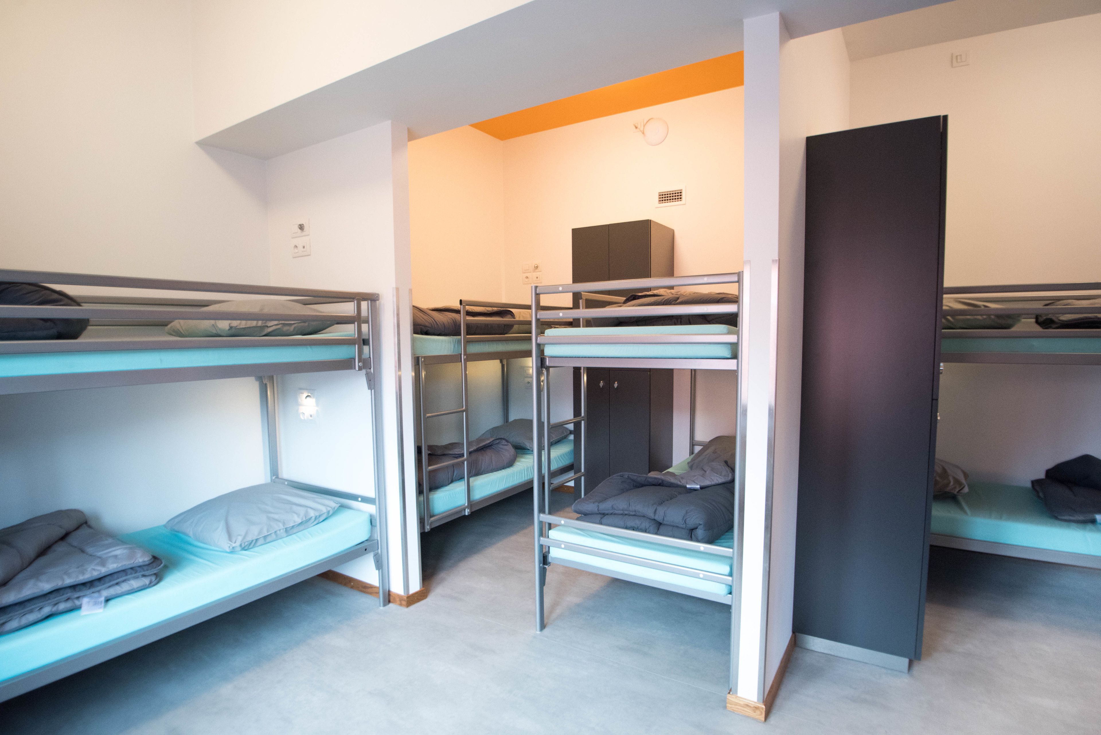 Un dormitorio con literas, un armario y una pequeña zona de kitchenette.